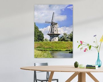 Traditionelle holländische Windmühle auf einem Deich mit blauem Himmel und Wolken von Tony Vingerhoets