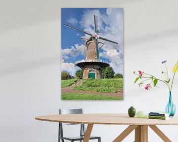 Traditionele Nederlandse windmolen op een dijk tegen een zonnige blauwe hemel van Tony Vingerhoets