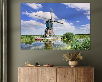 Karakteristiek Nederlandse windmolen dichtbij kanaal met weelderige plantengroei 1 van Tony Vingerhoets