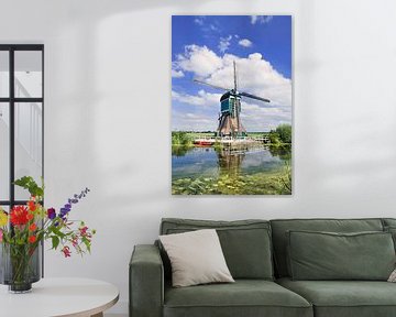 Karakteristiek Nederlandse windmolen dichtbij kanaal met weelderige plantengroei 2