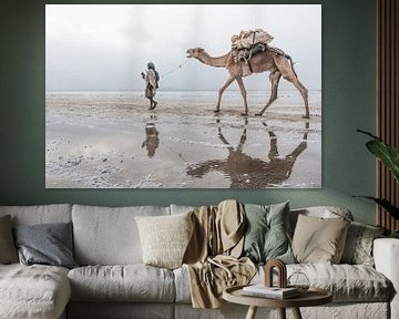 Un chameau et un homme marchent dans le désert en Éthiopie.