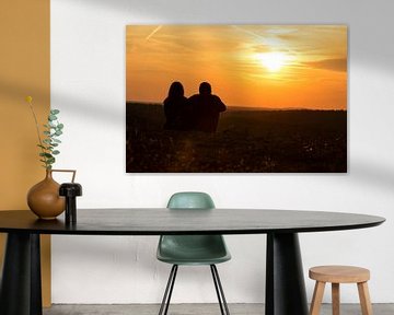 Un couple est assis dans la prairie et regarde le coucher de soleil