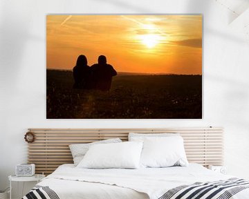 Ein Paar sitzt auf der Wiese und schaut in den Sonnenuntergang