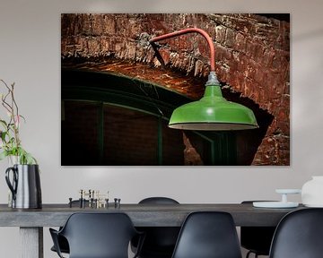 Groene metalen lamp op een stenen muur. van Jan van Dasler