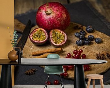 Wooden cutting board with pomegranate, passion fruit, berries, cinnamon sticks and star anise by Mayra Fotografie