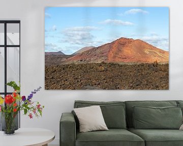 Lavavaveld en rode berg op de achtergrond op Lanzarote van Reiner Conrad