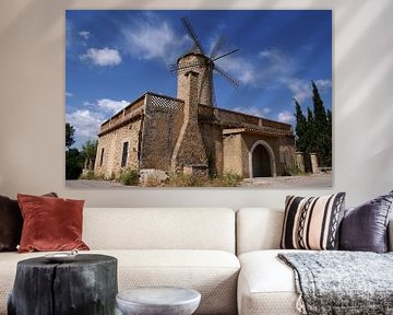 Steinhaus mit Windmühle vor blauem Himmel mit Wolken