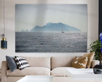 A sailboat sails off an island on the Amalfi coast in Italy
