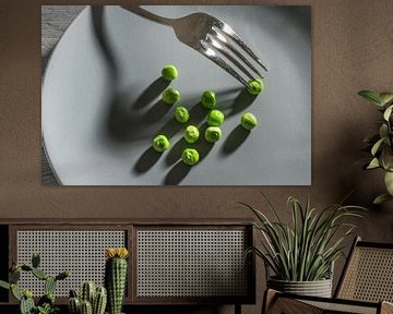Wat groene erwten en een vork met schaduwen op een grijs bord, magere dieetmaaltijd na het voornemen