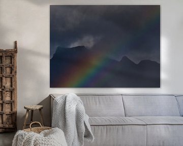 Strong, colorful rainbow in front of rugged mountains by Timon Schneider
