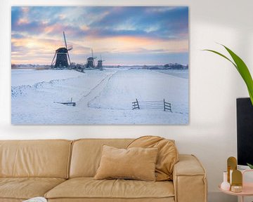 Trois moulins à vent au lever du soleil dans un paysage hivernal