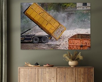 Vrachtwagen op een bouwplaats dumpt een container met stenen