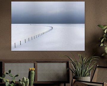Eine leere, schneebedeckte Winterlandschaft im Nationalpark Lauwersmeer. Am Horizont treiben dunkle 