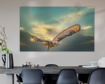 Ein eurasischer Uhu. Fliegt mit ausgebreiteten Flügeln gegen einen dramatischen Himmel.