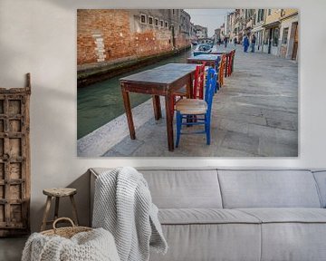 Tafeltjes met stoelen aan kanaal met boten in oude centrum Venetie, Italie