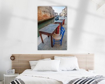 Tables et chaises sur un canal avec des bateaux dans le vieux centre de Venise, Italie sur Joost Adriaanse