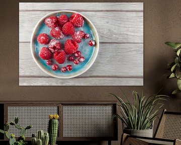 Himbeeren und rote Johannisbeeren auf einem Teller auf einer Holzunterlage. von Ans van Heck