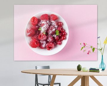 Frambozen en rode bessen in een wit schaaltje tegen een roze achtergrond. van Ans van Heck