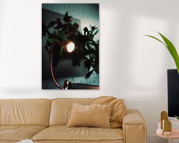Nice lamp with a plant behind it and a painting in the background.