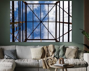Urbex Symmetrie - rostige Metallkonstruktion vor einem blauen Himmel mit Wolken