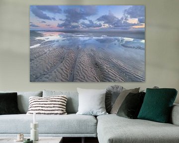 Eb op het strand van Westerschouwen op Schouwen Duivenland in Zeeland. De wolken weerspiegelen in he