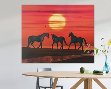 Drie paarden lopen naar elkaar toe op het strand