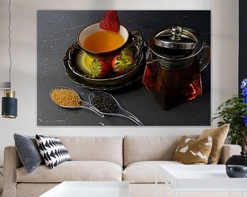 Schwarzer Tee mit Erdbeere in einer Tasse und einer Glaskanne mit Teea