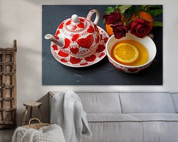 Schwarzer Tee serviert mit Orangenscheibe und roten Rosen
