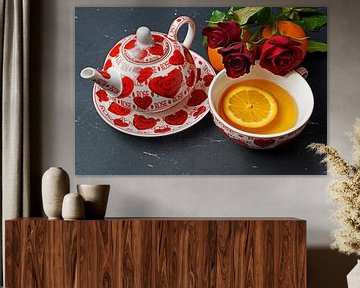 Schwarzer Tee serviert mit Orangenscheibe und roten Rosen