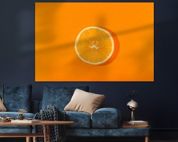 Schijfje sinaasappel tegen een oranje achtergond van Ans van Heck