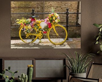 Un vieux vélo jaune décoré de fleurs est posé contre la clôture d'un canal à Gouda.