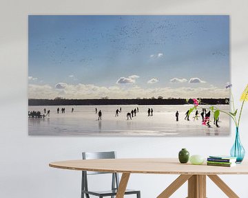 Ee vlucht vogels boven de schaatsers op het bevroren Paterswoldse meer in Groningen van Marc Venema