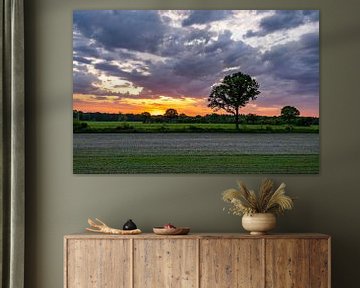 Zonsopkomst boven een groen landschap met oranje lucht en wolken van Dafne Vos