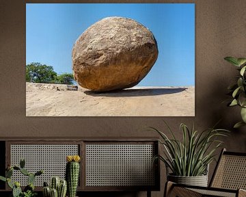 A giant round boulder stands on a hillside against a blue sky. by WorldWidePhotoWeb