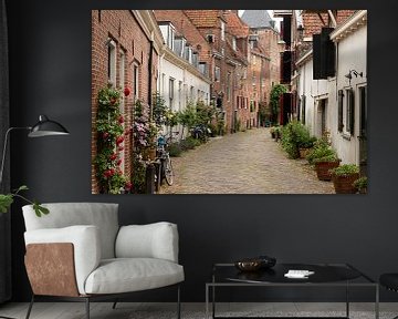 A narrow street with flowerpots by Jan van der Wolf