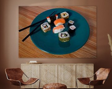 Sushi angeordnet auf einem grünen Teller mit Stäbchen