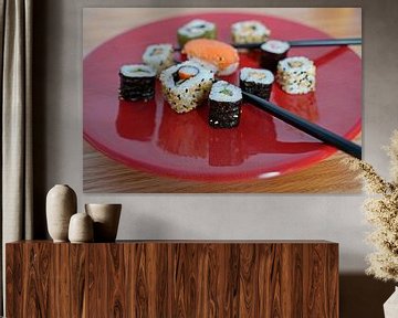Sushi auf einem roten Teller mit Stäbchen angeordnet