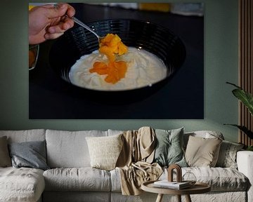 Spatel de mandarijnen met een lepel door het kwark- en yoghurtmengsel in een kom. van Babetts Bildergalerie
