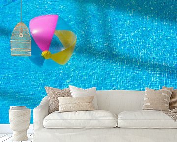 Inflatable colorful beach ball float on rippled blue swimming pool by Alex Winter