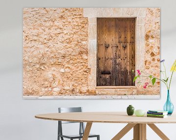 Detail view on an mediterranean house stone wall with old wooden door by Alex Winter