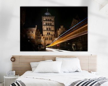 Lichtspuren eines Busses, der durch den Burgtorturm von Lübeck bei Nacht fährt, historischer Backste von Maren Winter