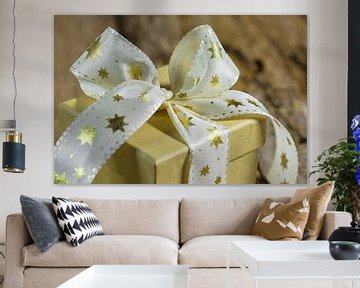 Weihnachtsgeschenk mit goldener sternförmiger Schleife auf Holztisch von Alex Winter