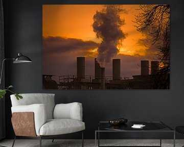 Rokende schoorstenen van een fabriek in de ondergaande zon van ManfredFotos