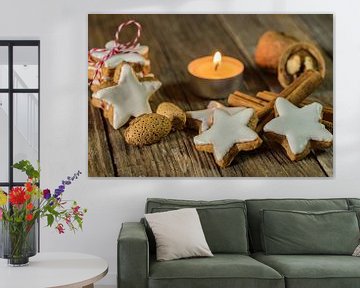 Kerstster koekjes, kaneelkruiden, noten en kaarslicht op houten tafel van Alex Winter