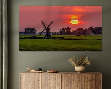 Ondergaande zon met molen friese landschap. van piet douma