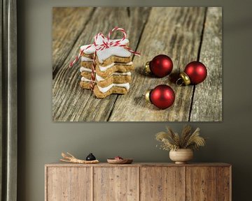 Sternförmige Weihnachtsplätzchen stapeln sich auf einem Holztisch mit roten Kugeln von Alex Winter