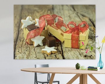 Christmas pastry and chocolate in gift box with red ribbon on wooden table by Alex Winter