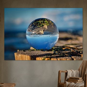 Sphère en verre sur un épi de la mer Baltique. L'épi se reflète dans la sphère.