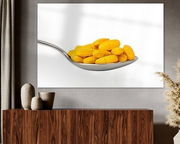 Big spoon with many yellow pills by Frank Herrmann
