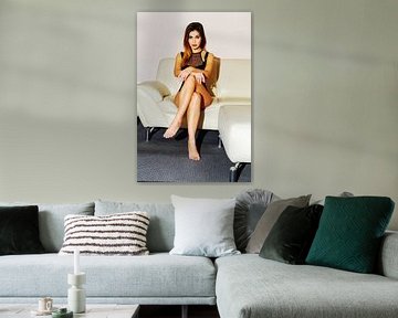 Eine hübsche junge Frau sitzt auf dem Sofa von Rainer Zapka